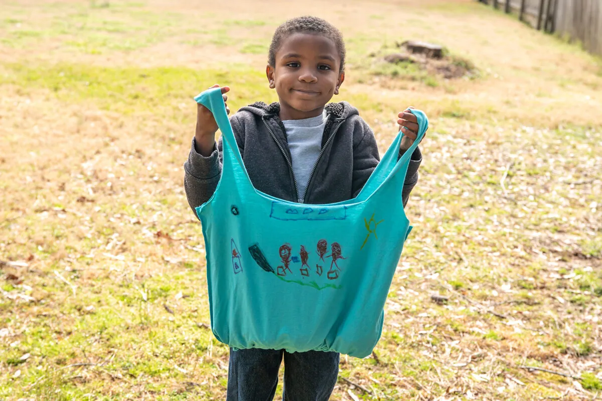 A child holding a reusable bag made from a t-shirt
